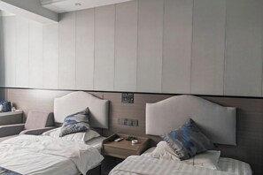 A hotel room with two beds, a nightstand, and a wall-mounted control panel. - Shun Xing Hotel (Dali City)