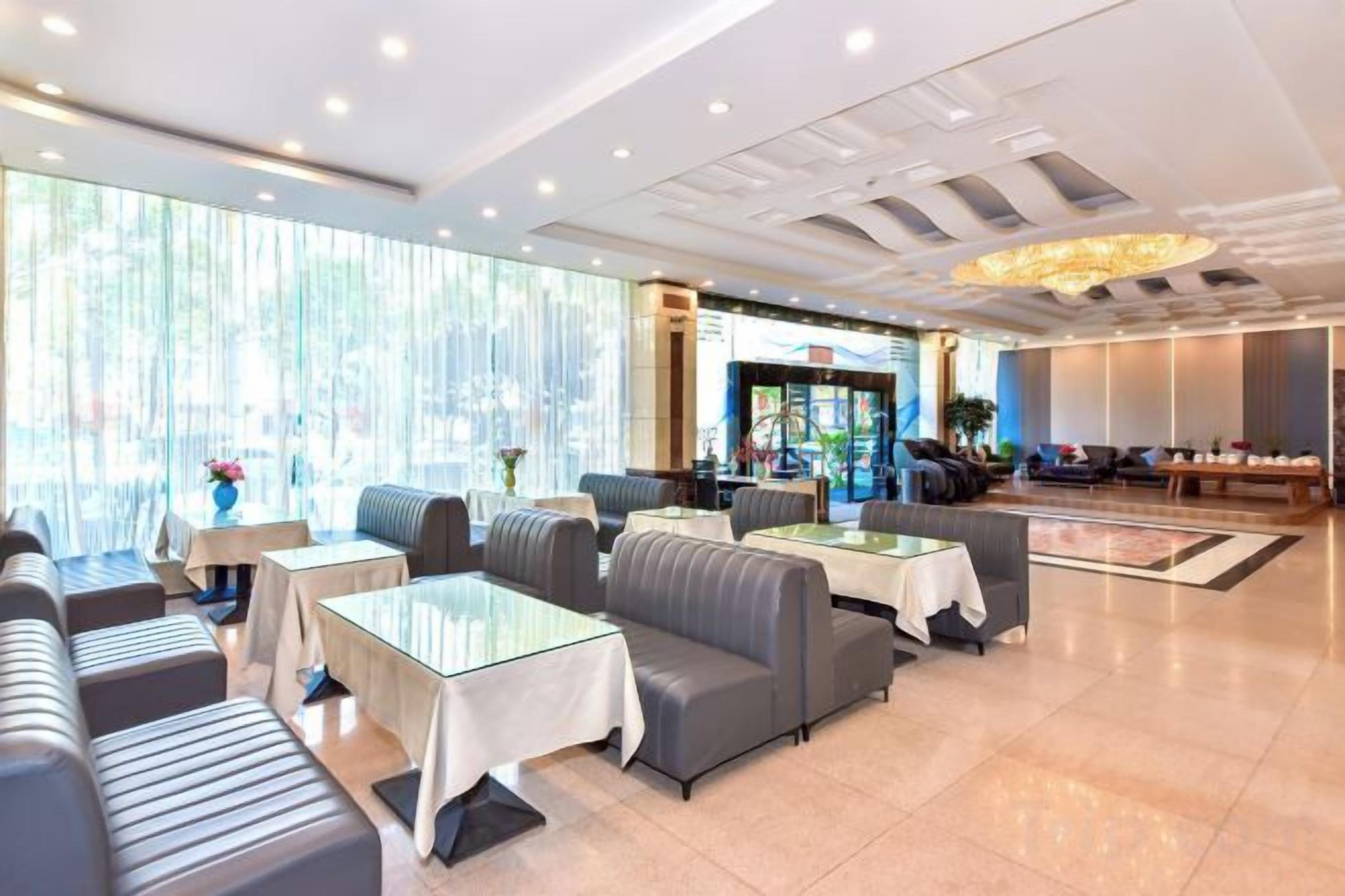 Un vestíbulo de hotel con zonas de estar, mesas y una recepción.