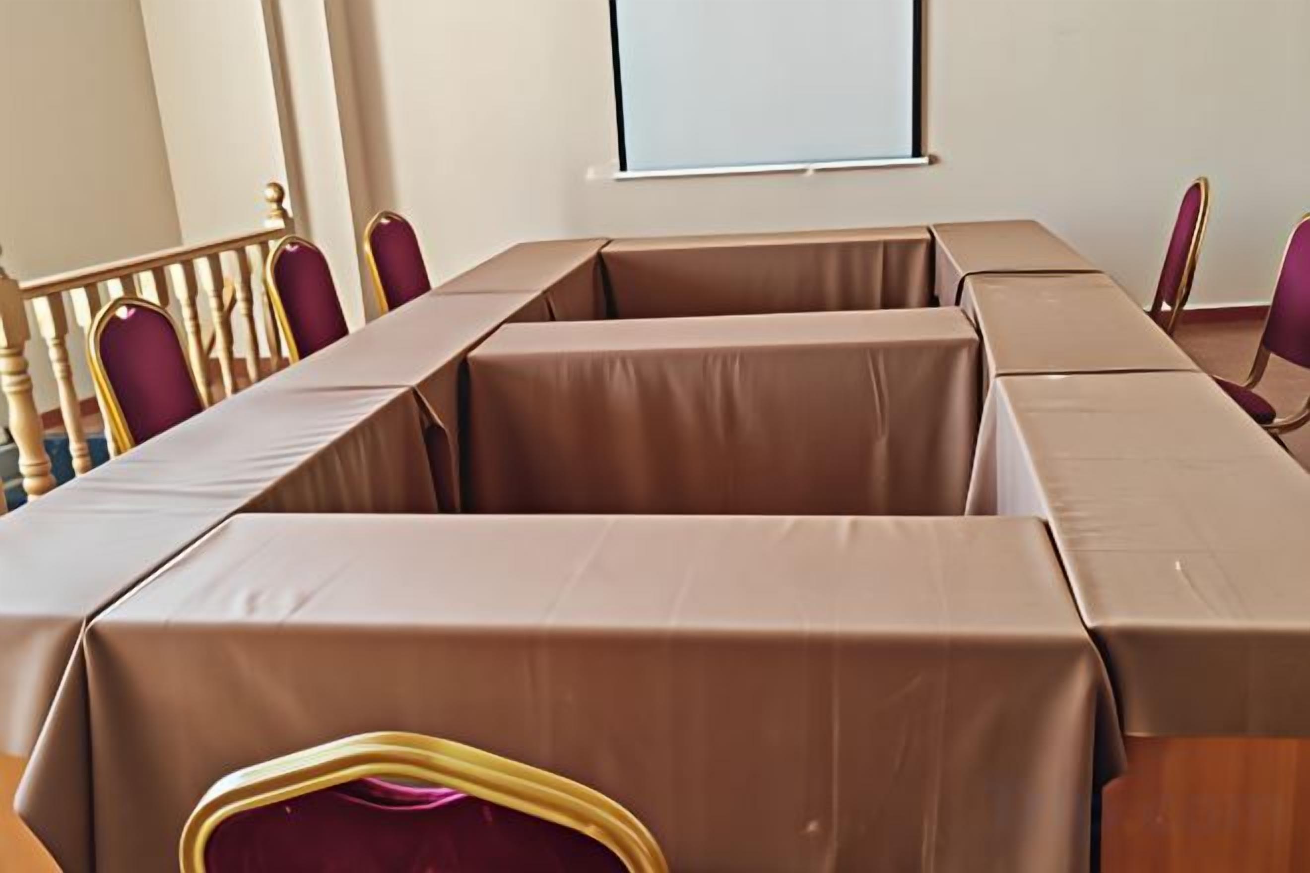 A conference room with a long table, chairs, and a projector screen.