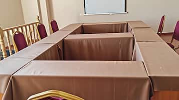 A conference room with a long table, chairs, and a projector screen.