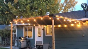 A covered patio area with string lights, a grill, and outdoor furniture. - Walk to Downtown [] Game Room [] Private Fenced Yard (Fruita)