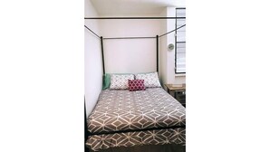 A room with a four-poster bed, a green throw pillow, and a red pillow. - Penthouse in San Juan, 2 Beds, Comfortable A/C (San Juan)