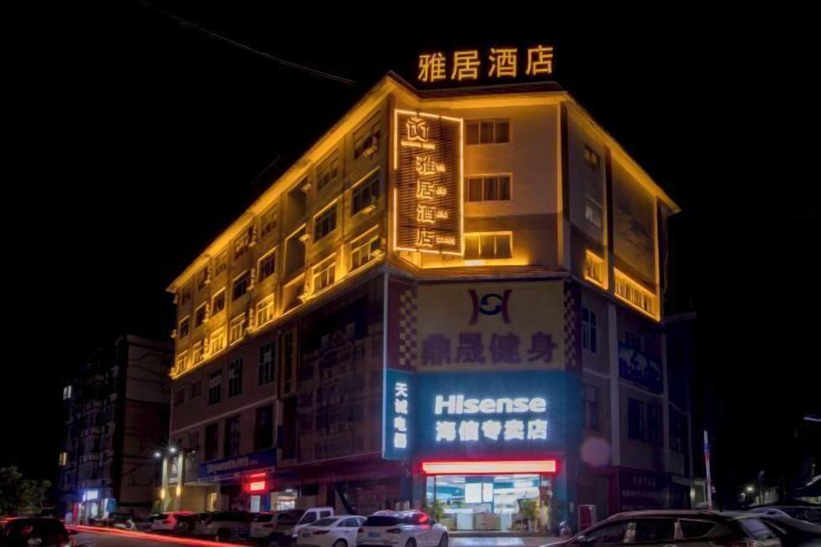 A hotel building with illuminated signage, including a prominent 'Hisense' sign and a '雅居酒店' sign.