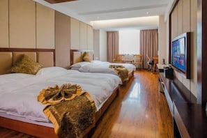 A hotel room with two beds, a TV, and a seating area with a chair and table. - Yaju Hotel (Lancang)