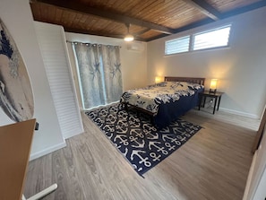 Une chambre à coucher avec un lit, une fenêtre, un ventilateur de plafond et un tapis à motifs.