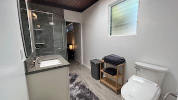 A bathroom with a sink, toilet, and a window.