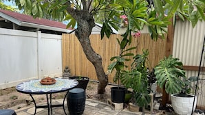 Un patio con una mesa redonda, plantas en macetas y una valla de madera.