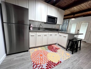 Une cuisine moderne dotée d’appareils électroménagers en acier inoxydable, de meubles blancs et d’un tapis aux couleurs vives.