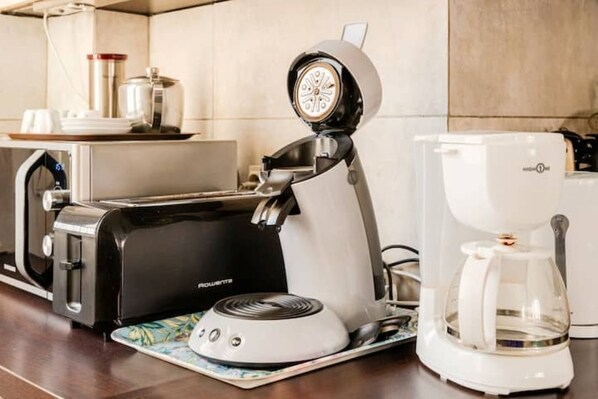 A kitchen with a coffee maker, a toaster, and a kettle on the counter.