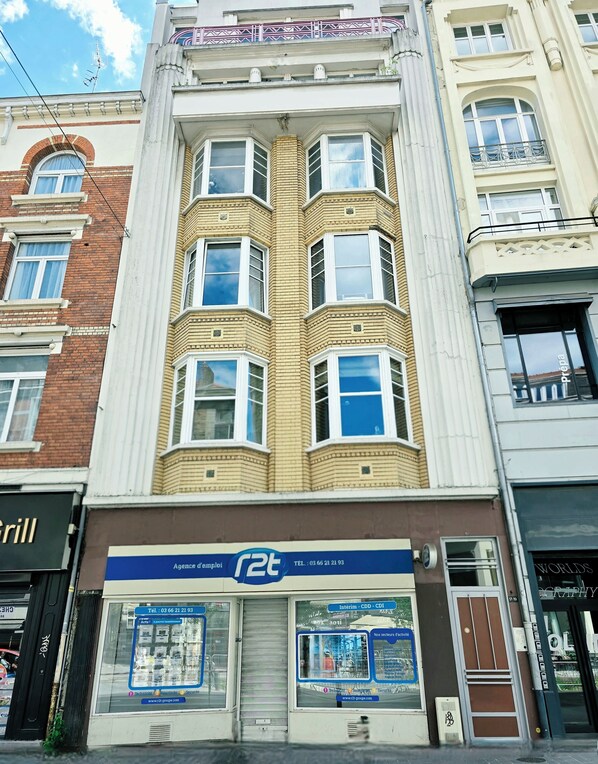 A multi-story building with a ground-floor shop named 'r2t' and a visible storefront with a closed shutter.