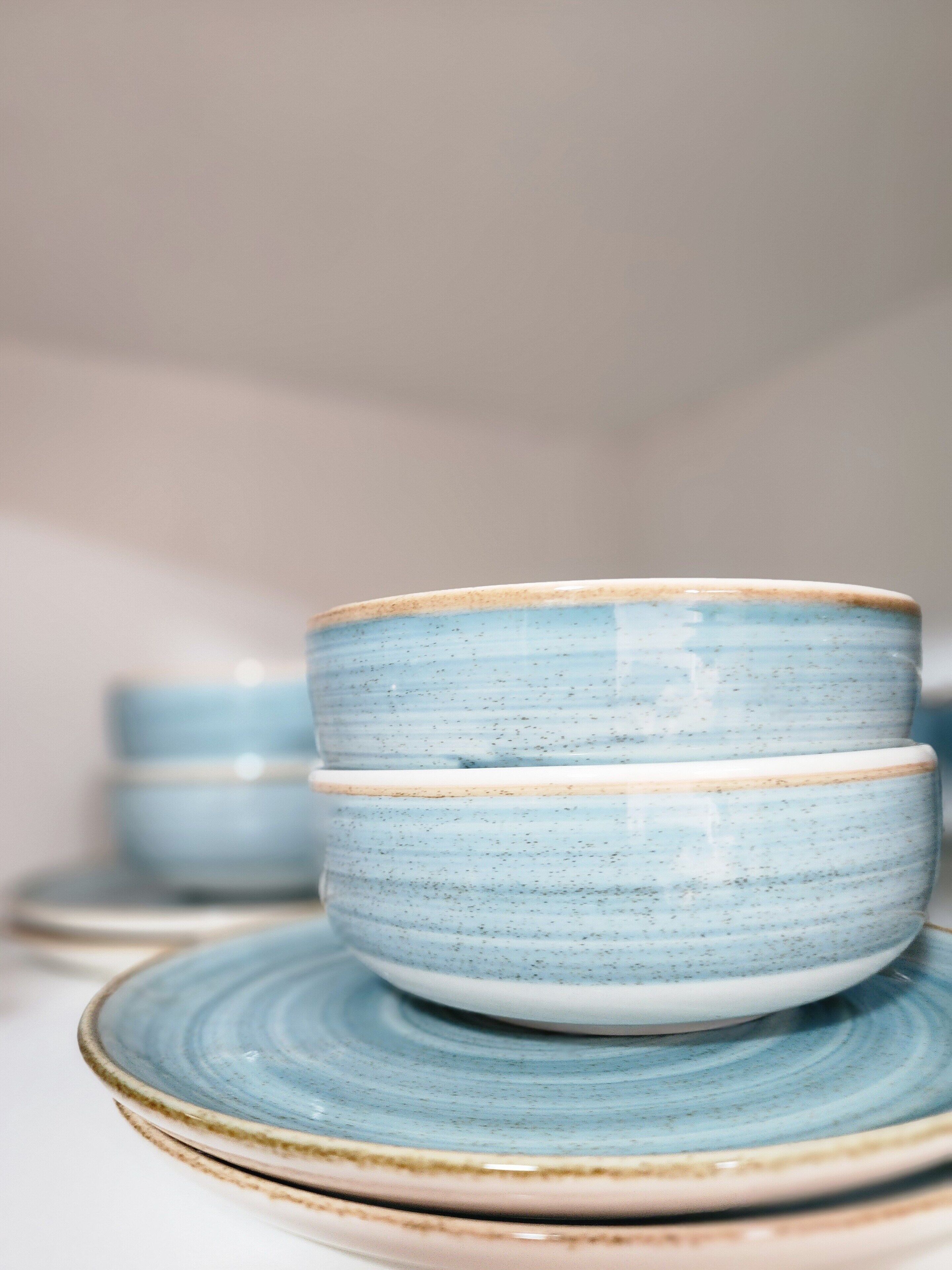 A stack of ceramic bowls with a blue and white speckled pattern, placed on matching plates.