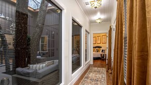 A hallway with a large window, a sofa, and a rug. - Creek Treehouse Atrium Hot Tub Buffalo (St Joe)