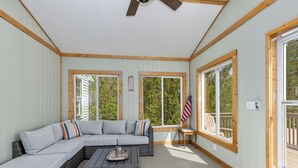 A sunlit room with a large sectional sofa, a small table, and a ceiling fan. - Spacious Country Home & 15 minutes from Lake Michigan
 (Grand Junction)