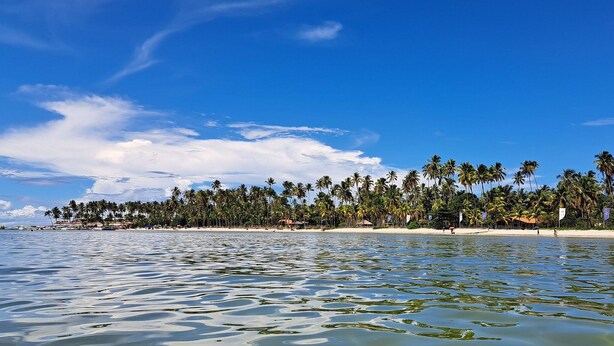 Na praia, areia branca, espreguiçadeiras, guarda-sóis 