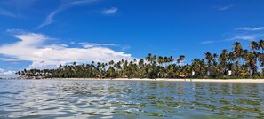 Na praia, areia branca, espreguiçadeiras, guarda-sóis