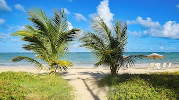 Na praia, areia branca, espreguiçadeiras, guarda-sóis