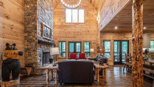 A log cabin interior with a fireplace, a sofa, and a dining area.