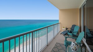 A balcony with a view of the ocean, two chairs, a small table, and a decorative lantern. - ⛱️Gulf Front Master-3BR Majestic Beach Towers 1-1804⛱️ (Panama City Beach)