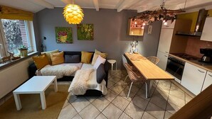 A cozy living room with a sofa, a dining table, and a kitchen area. - Lovely apartment on the Wadden Sea, suitable for children and tierlieb♥️ (Wangerland)