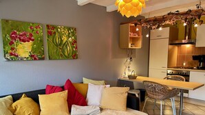 A modern living room with a sofa, a dining table, and a kitchen area. - Lovely apartment on the Wadden Sea, suitable for children and tierlieb♥️ (Wangerland)
