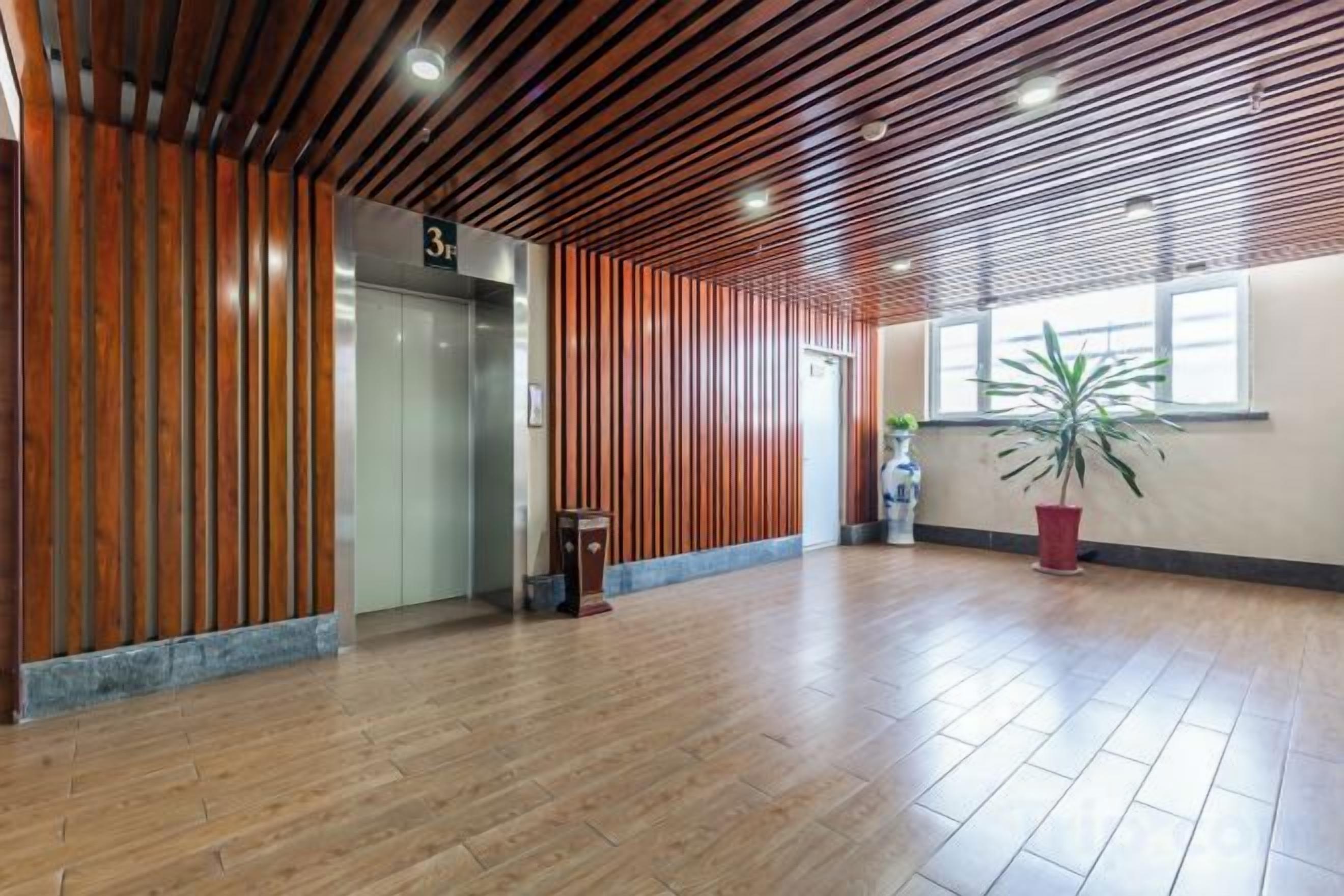 Un vestíbulo espacioso con paneles de madera, un mostrador de recepción y una planta en maceta.