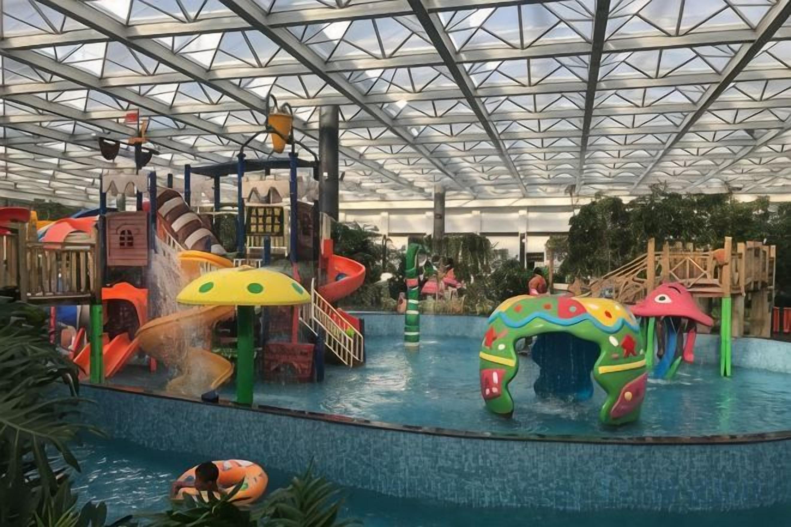 An indoor water park with slides, a pool, and play structures.