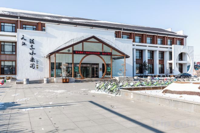 A modern building with a large entrance, a signboard, and a parking area with bicycles.
