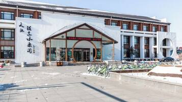 A modern building with a large entrance, a signboard, and a parking area with bicycles.