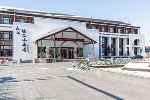 A modern building with a large entrance, a signboard, and a parking area with bicycles. - Tianyuan Jibushi Hot Spring Hotel (Haicheng)