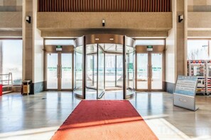 Puerta giratoria de acceso con una alfombra roja que conduce a un vestíbulo.