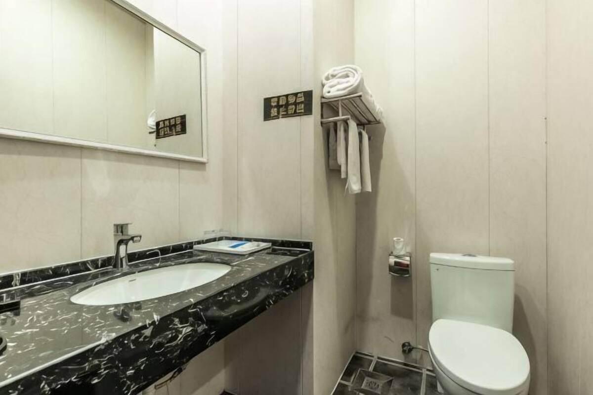 A bathroom with a marble sink, a toilet, a towel rack, and a mirror.