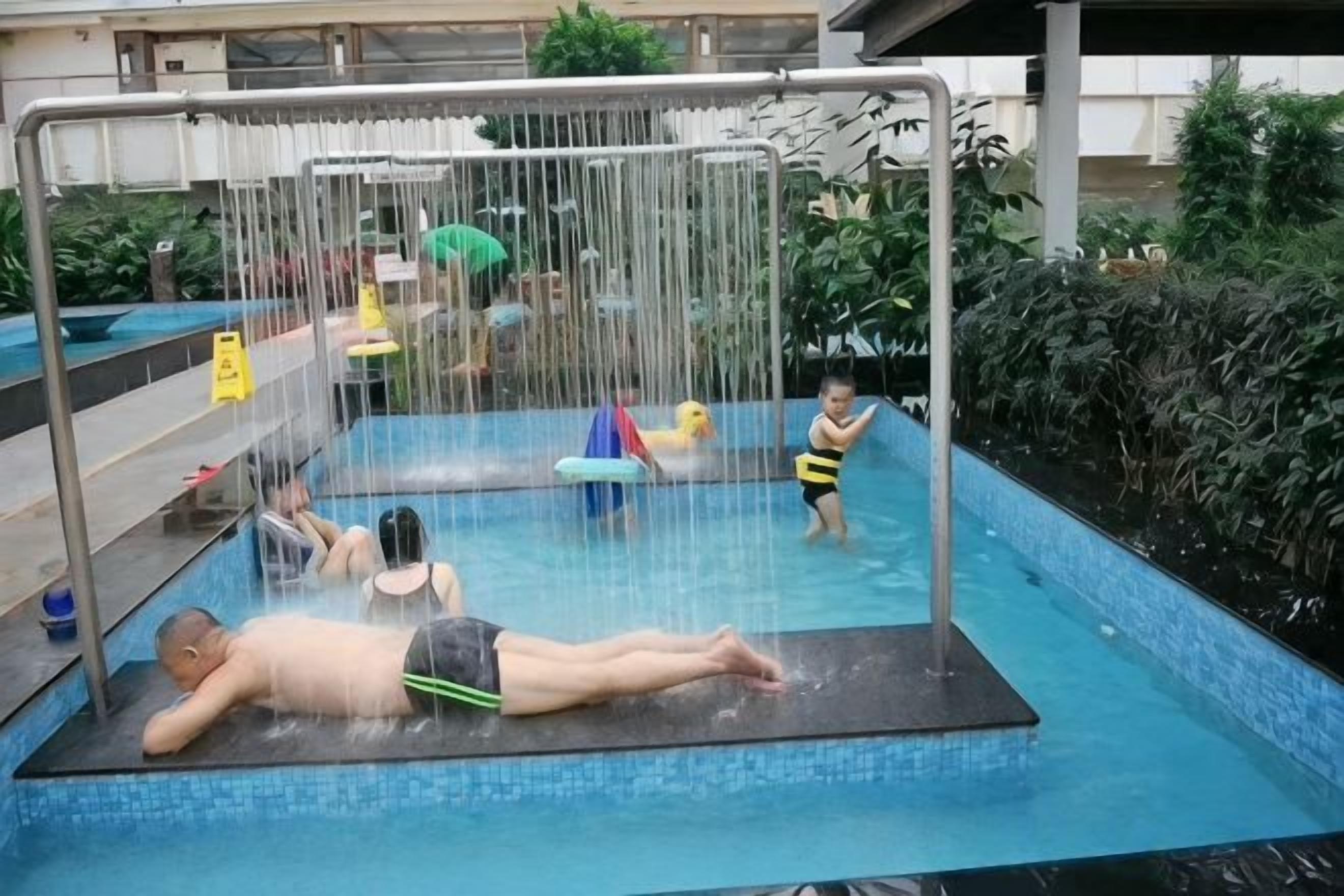 Una piscina con fuente de agua, rodeada de vegetación.