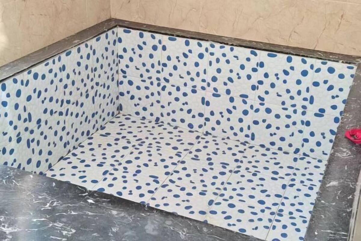 A tiled bathroom with a white base and blue polka dots.
