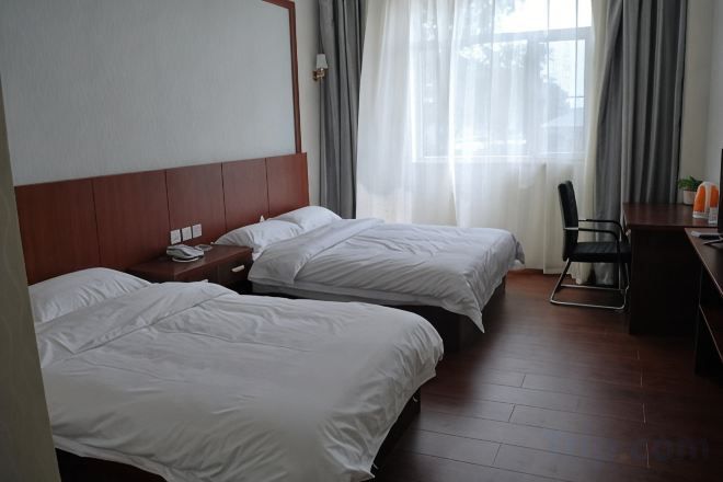 A hotel room with two beds, a desk, and a chair.