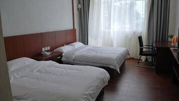 A hotel room with two beds, a desk, and a chair.