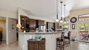 Une cuisine spacieuse avec des meubles en bois foncé, un îlot central et des luminaires suspendus.