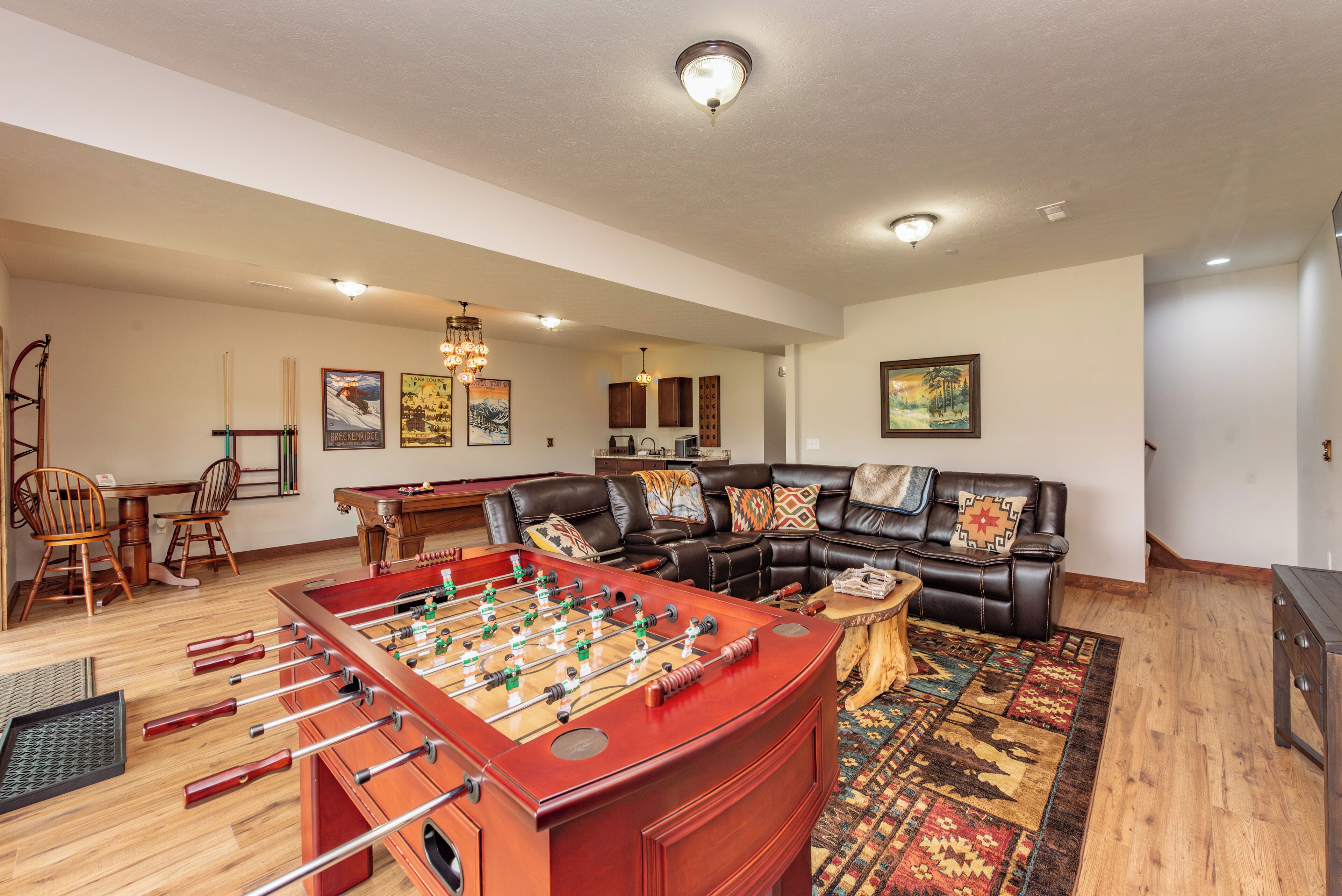 A spacious living room with a foosball table, a leather sofa, a dining area with chairs, and a coffee table.