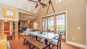 A spacious dining area with a large table and benches, a ceiling fan, and a view of the outdoors. - Stunning Views & Dog Friendly Style w/ Hot Tub (McHenry)