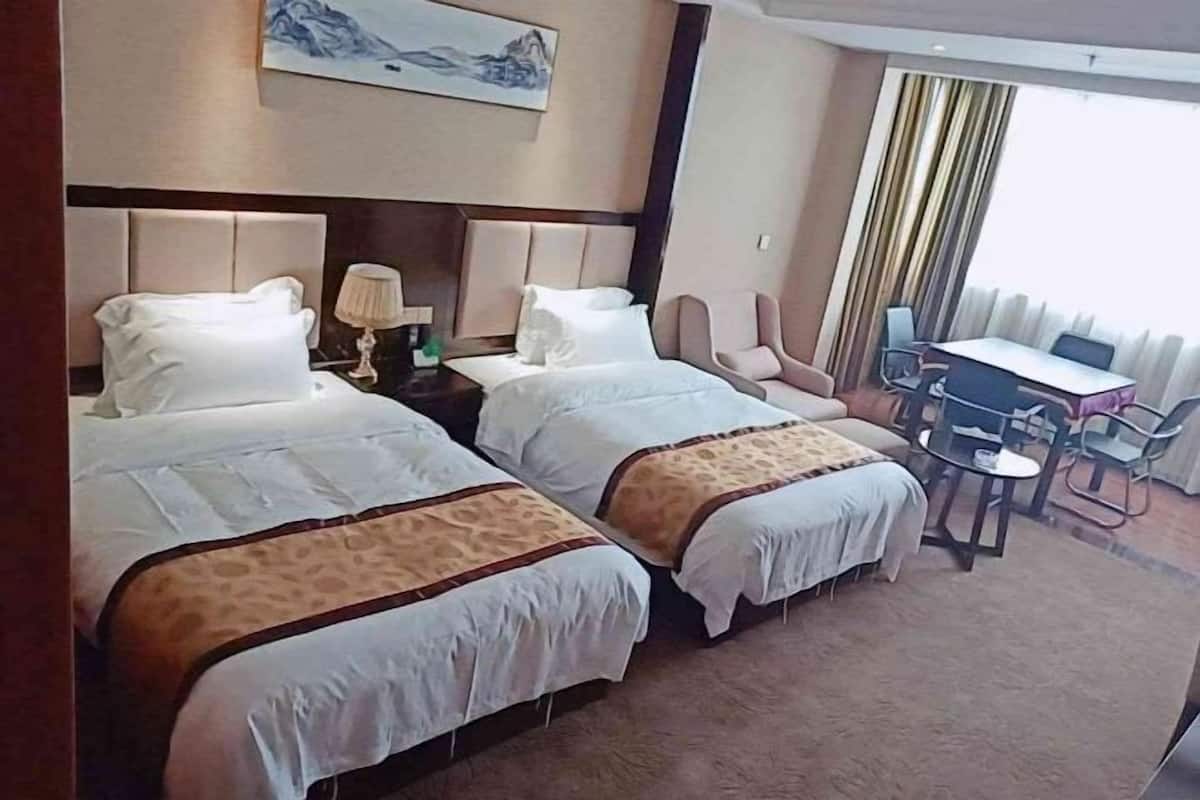 Une chambre d’hôtel avec deux lits, un bureau et une chaise.