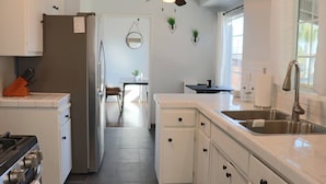 Una cocina moderna con armarios blancos, un lavamanos de acero inoxidable y un comedor con mesa y sillas.