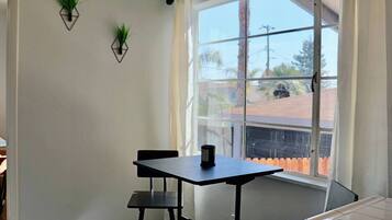 Une pièce dotée d’une grande fenêtre, d’une table avec deux chaises et de deux plantes fixées au mur.