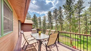 Eine Holzterrasse mit Tisch und Stühlen mit Blick auf ein bewaldetes Gebiet.
