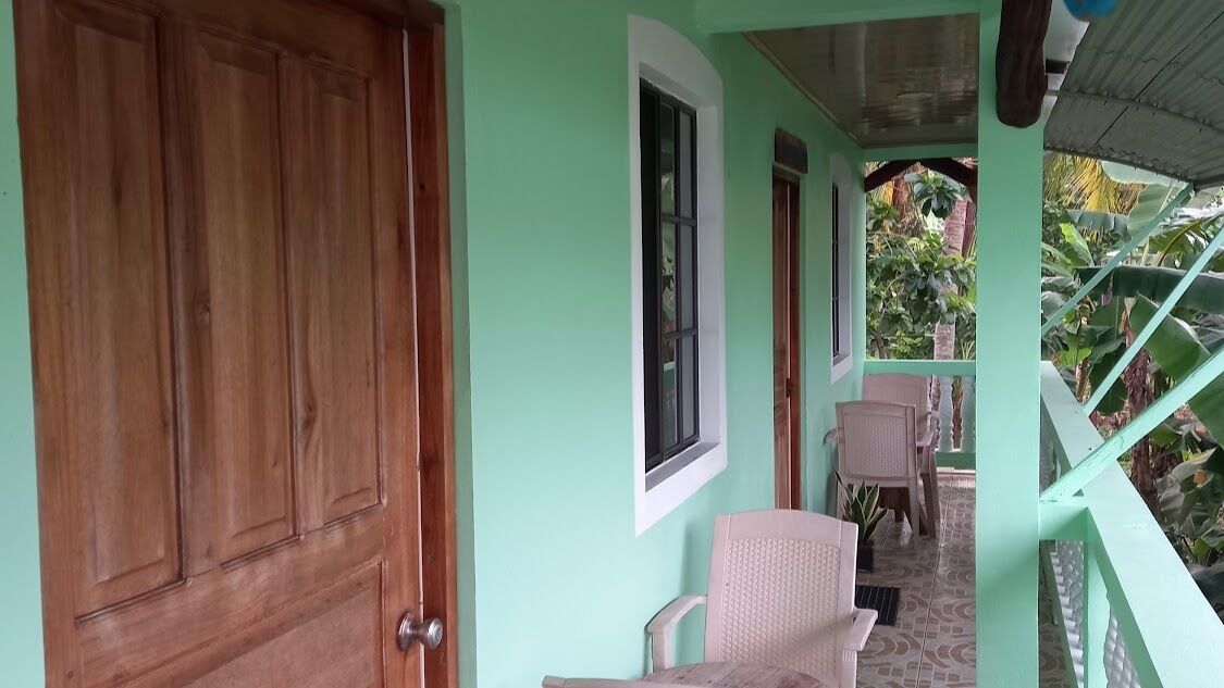 A room with a wooden door, a window, and a chair near a staircase.