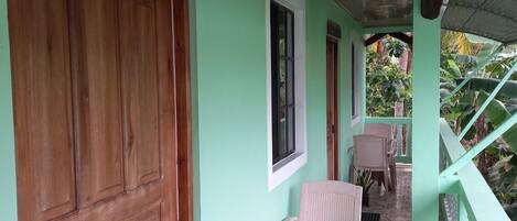 A room with a wooden door, a window, and a chair near a staircase.