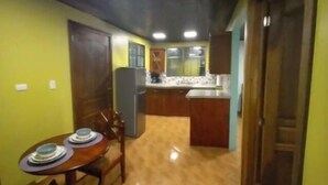 A kitchen with a dining area, wooden cabinets, a refrigerator, and a tiled floor.