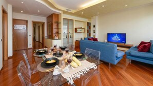 Un salon moderne avec un canapé bleu, une table à manger dressée et une télévision affichant le logo de la chaîne Disney Channel.