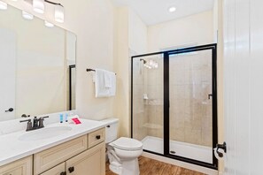 Bright bathroom of the cottage in Kissimmee Florida - Indulge in a refreshing experience with a walk-in shower stall - Chic vanity with large mirror and upscale lighting - Disney near: 2BR Cottage w/ Balcony & Jacuzzi Joy (Kissimmee)