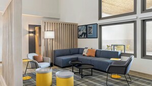 A modern living room with a sectional sofa, two armchairs, a coffee table, and a dining area with a table and chairs. - City Express by Marriott Bemidji (Bemidji)