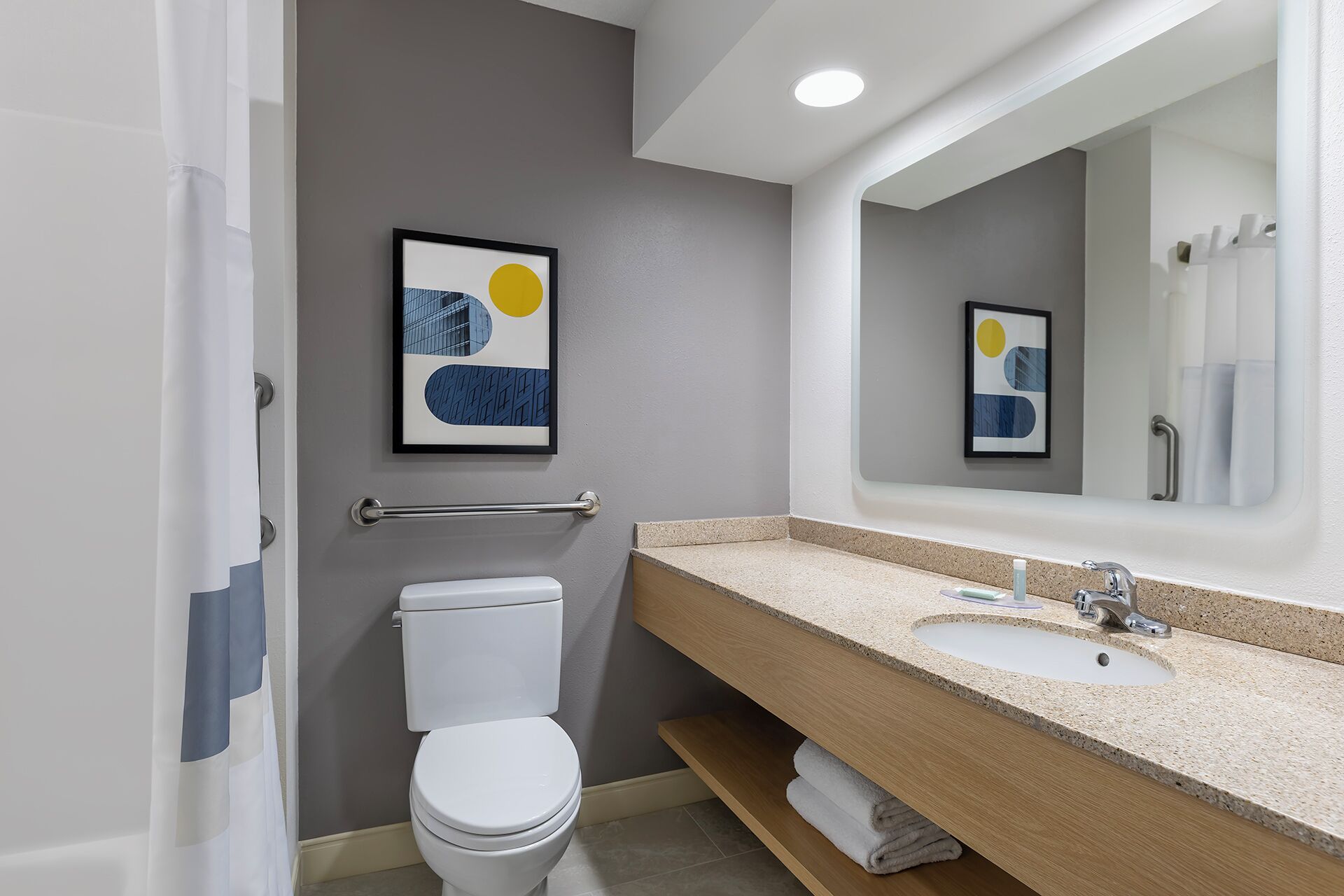 Un baño moderno con inodoro, lavamanos y espejo.