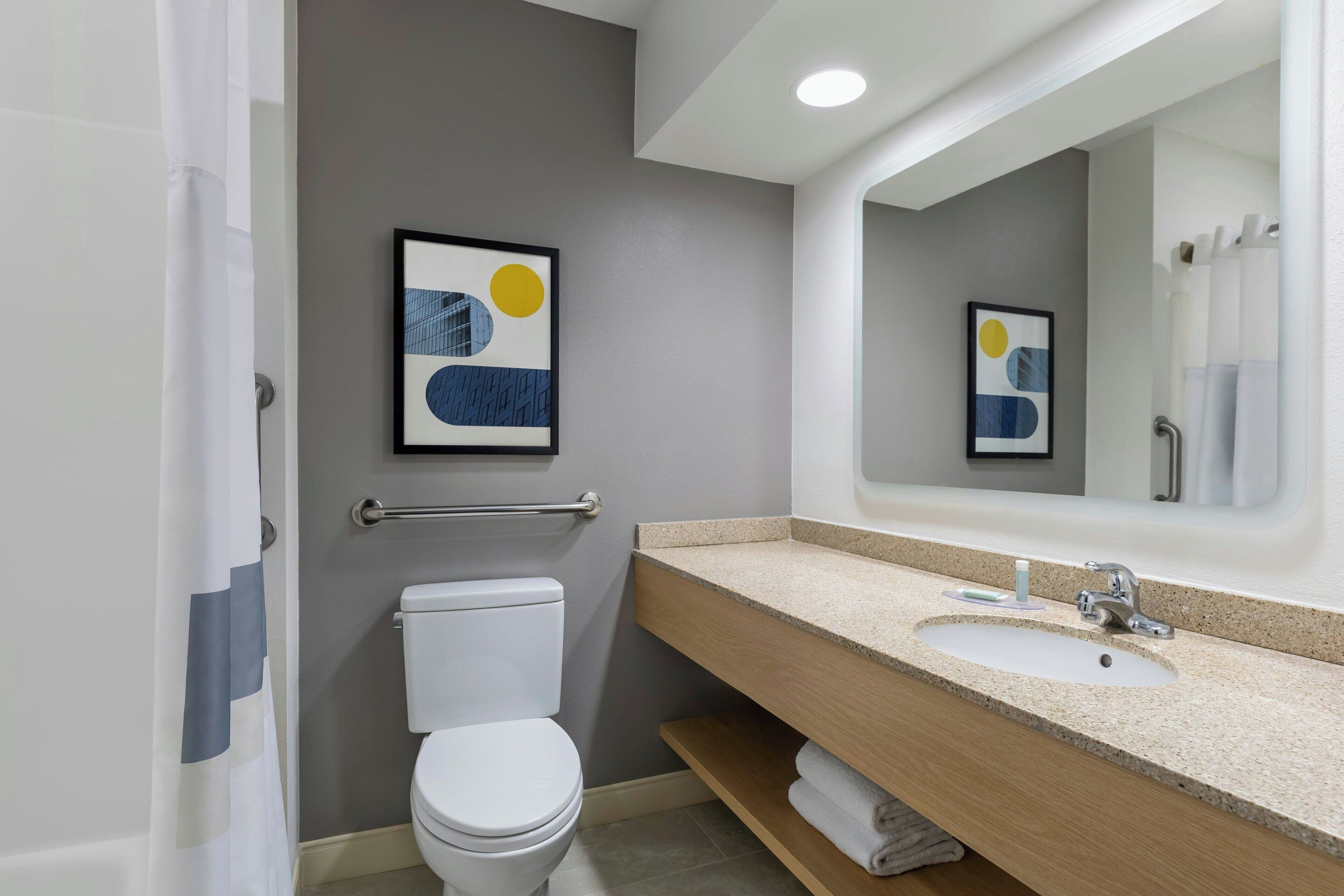 Un baño moderno con inodoro, lavamanos y cortina de ducha.